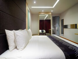 Une chambre d’hôtel moderne dotée d’un grand lit, d’un miroir, d’un dressing et d’une salle de bain.