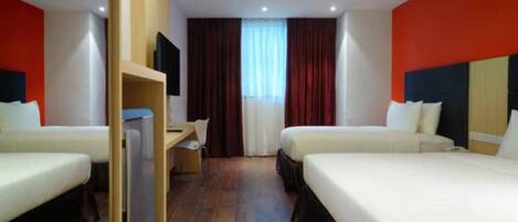 A hotel room with two beds, a desk, and a television.