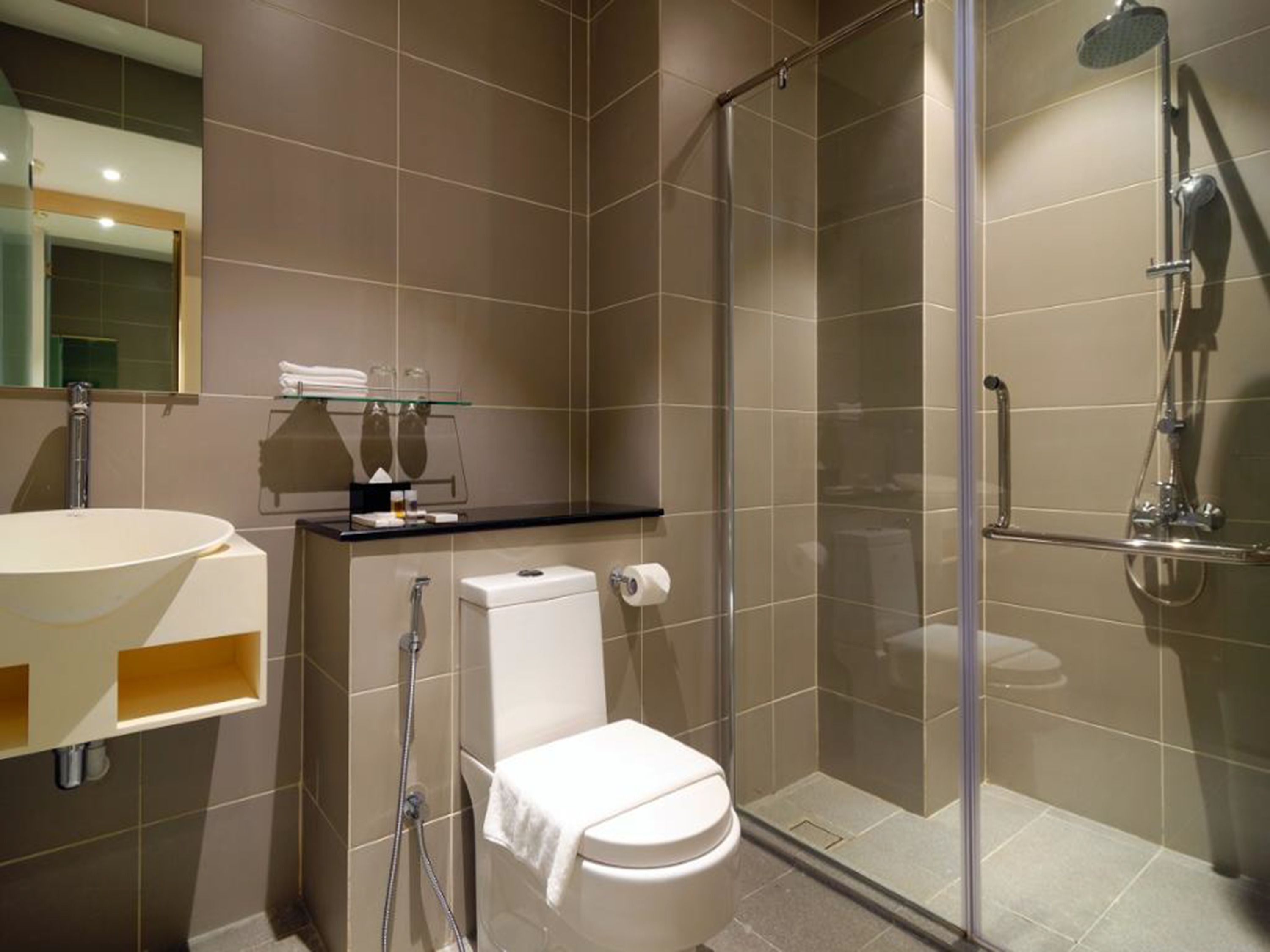 Une salle de bain moderne avec une douche à parois de verre, des toilettes blanches et un meuble-lavabo avec un évier et un miroir.