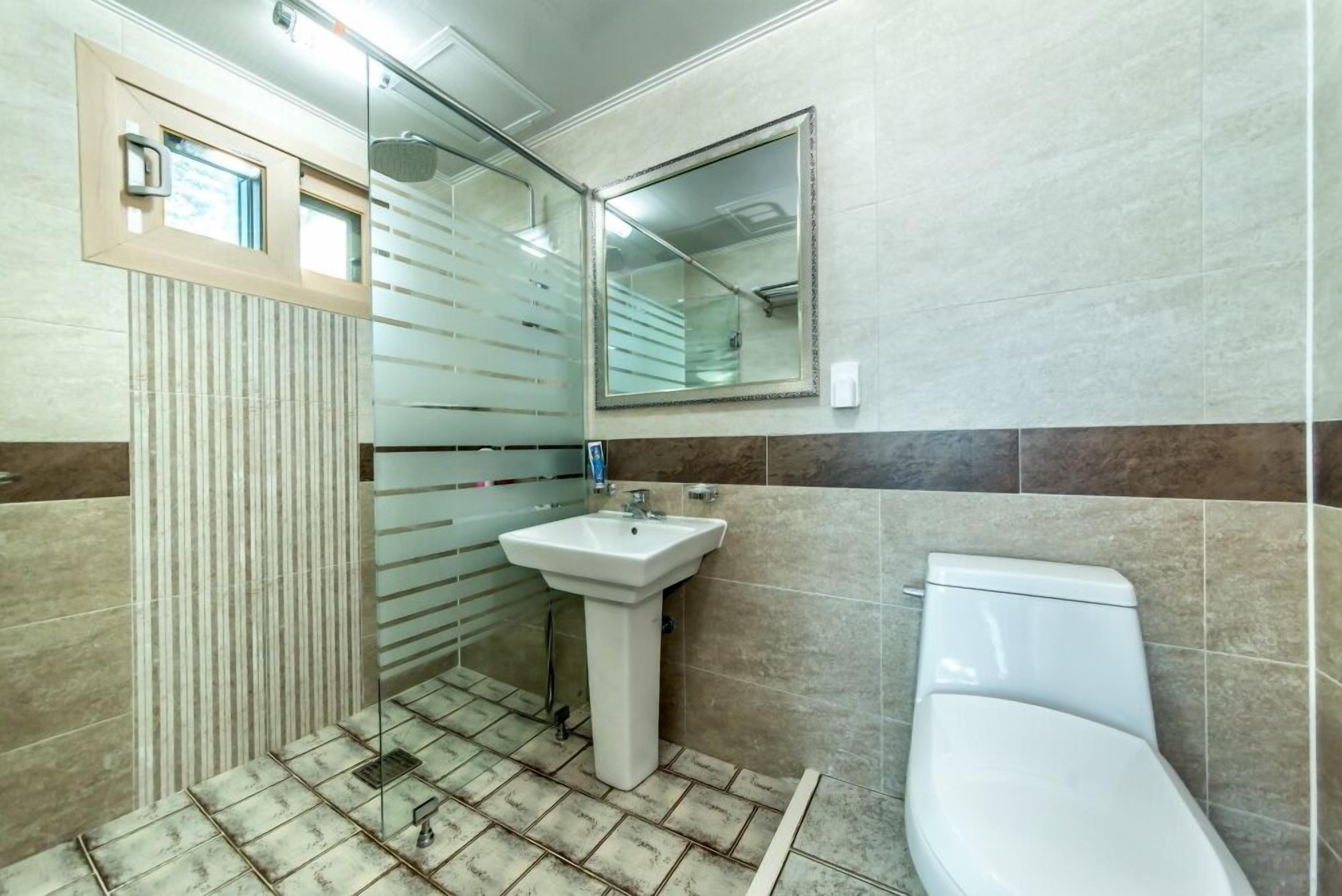 Een badkamer met betegelde vloer, een wastafel, toilet en een douchecabine van glas.