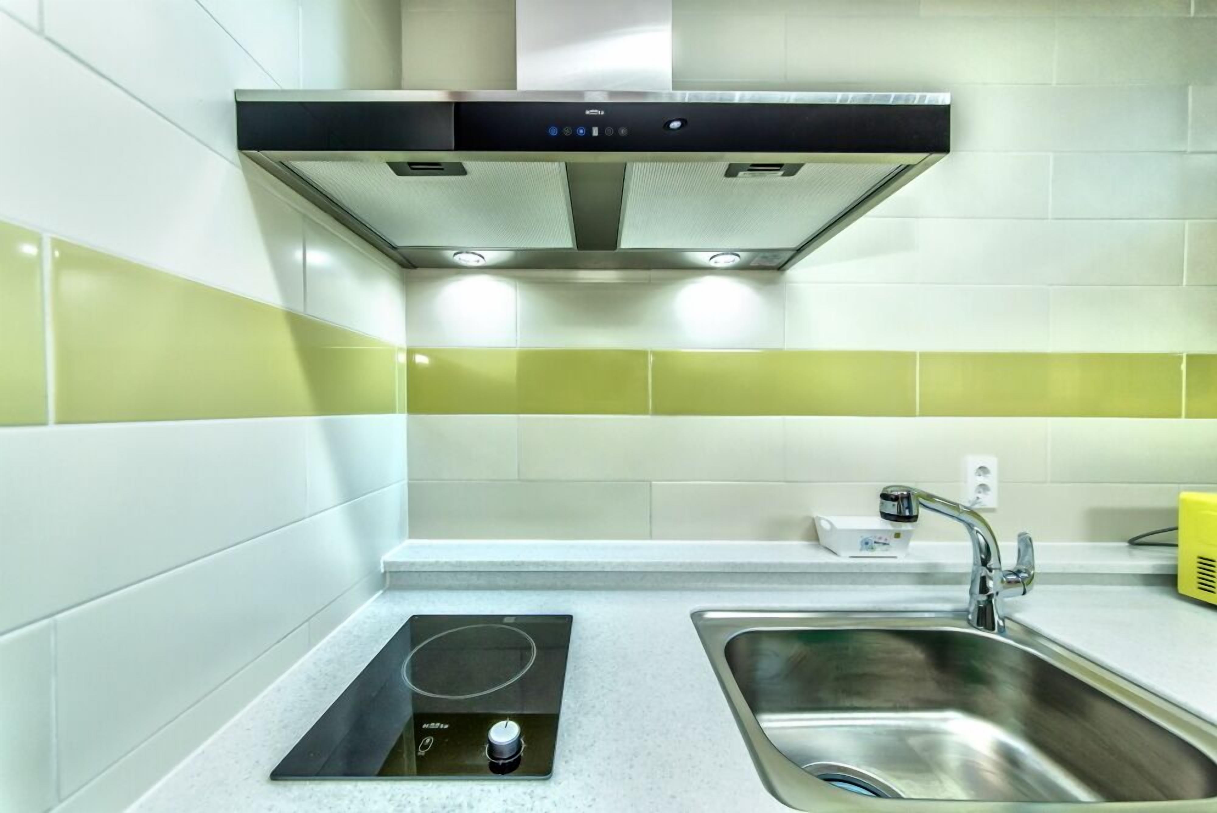 A modern kitchen with a built-in stove, a stainless steel sink, and a range hood.