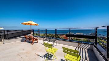 Relax on the balcony with ocean views, a pair of chairs, and a shaded area under the umbrella.