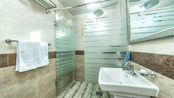 A bathroom with a glass shower enclosure, a white sink, and a towel rack.