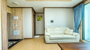 Una sala de estar moderna con techo de madera, sofá color beige y un ventanal con cortinas.