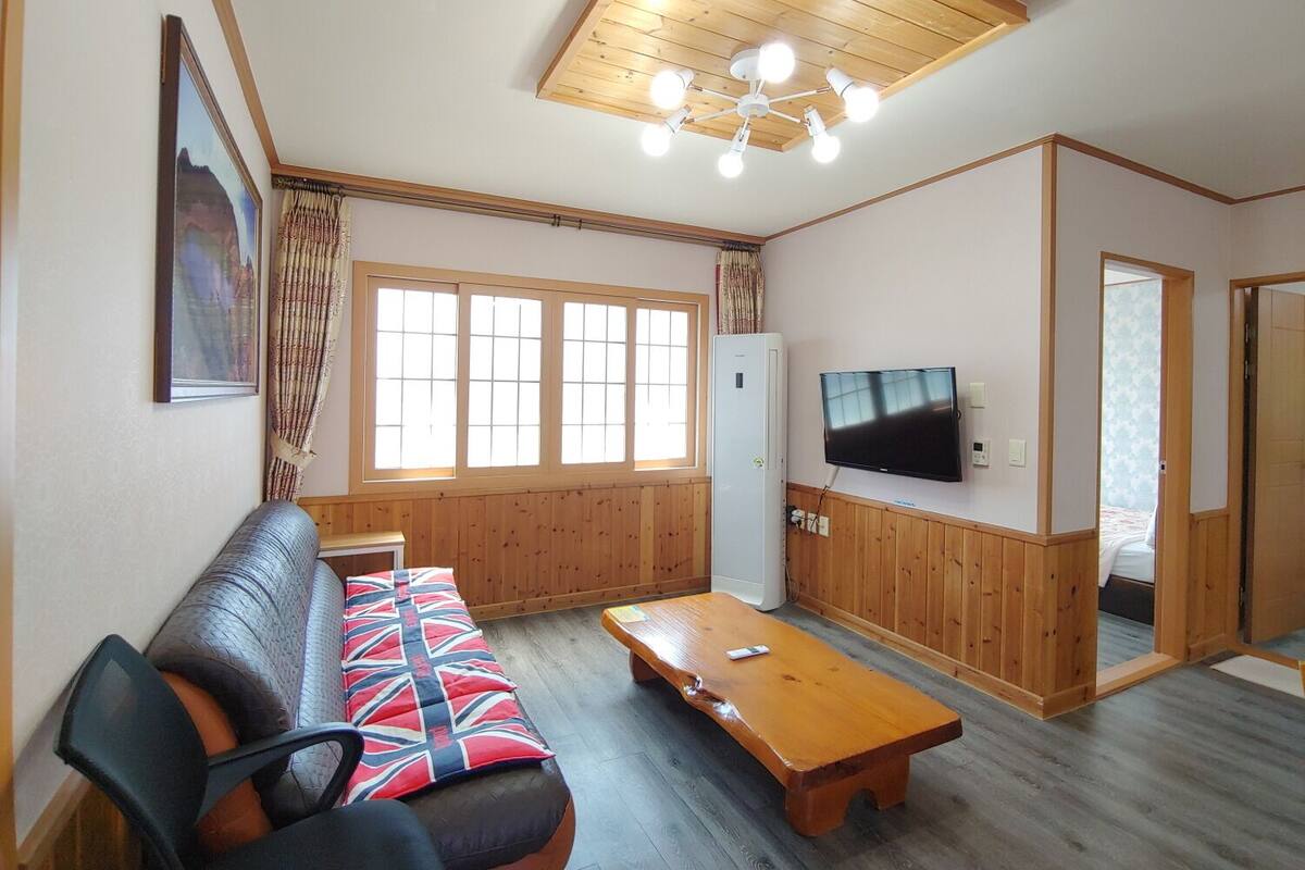 Una sala de estar con un sofá, una mesa de centro de madera, un televisor y un ventilador de techo.