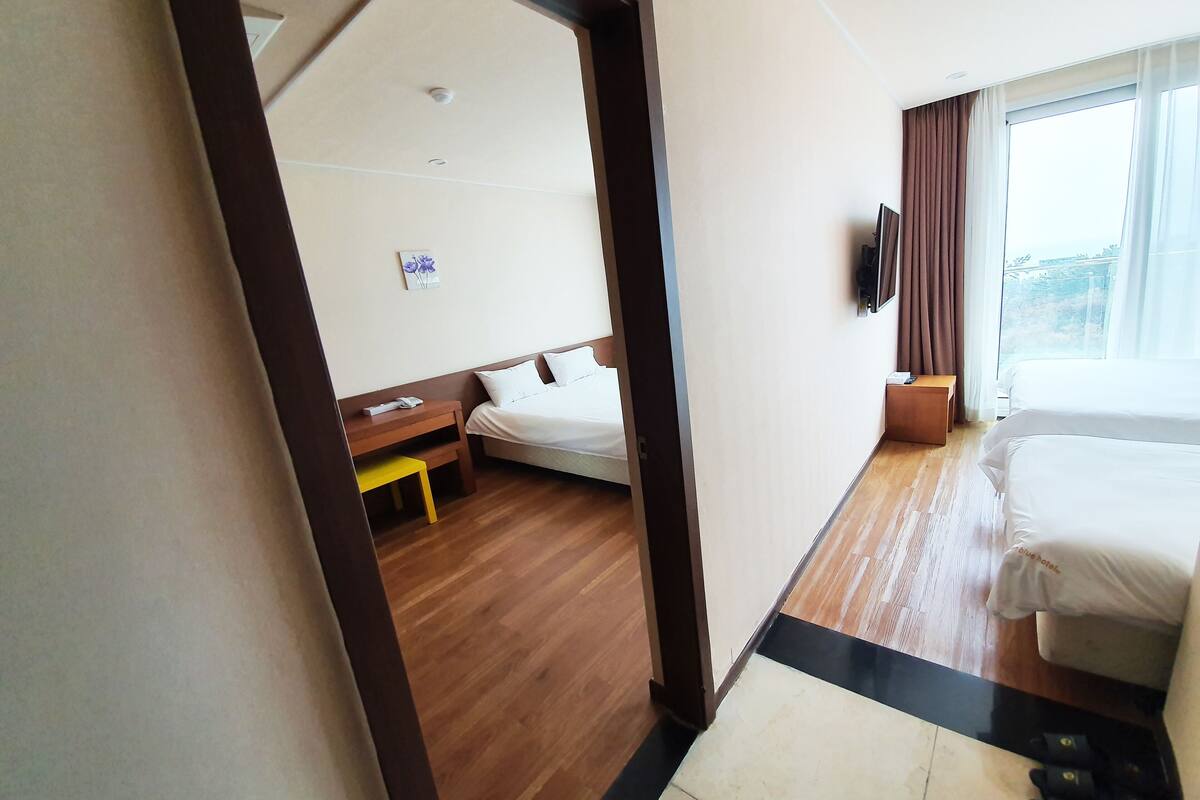 Quarto de hotel com cama, mesa de cabeceira e pequena escrivaninha com cadeira.