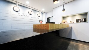 Un mostrador de recepción con encimera de madera, un reloj de pared y un cuadro enmarcado.