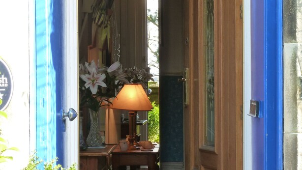 A doorway leading to a room with a wooden door, a small table with a lamp, and a sign above the door. - Failte Bed and Breakfast (Oban)