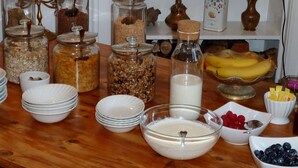 A kitchen counter with various food items, including jars of grains, a bottle of milk, and bowls of berries. - Failte Bed and Breakfast (Oban)
