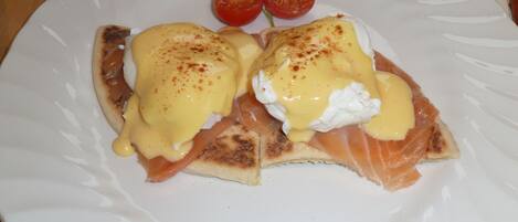 A plate with eggs benedict, smoked salmon, and cherry tomatoes.