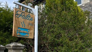 A wooden sign with the name 'Faile' and a bed symbol, indicating a bed and breakfast. - Failte Bed and Breakfast (Oban)