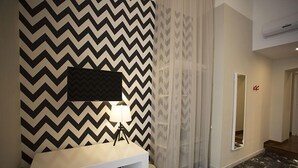 A modern bathroom with a black and white chevron-patterned wall, a white vanity with a mirror, and a black marble floor. - B&B Rettifilo (Naples)