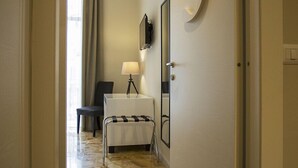 A hotel hallway with a marble floor, a bed, a desk with a lamp, a chair, and a large number '3' on the wall. - B&B Rettifilo (Naples)