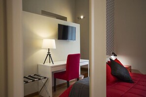 Une chambre d’hôtel équipée d’un lit, d’un bureau, d’une chaise, d’un téléviseur fixé au mur et d’une lampe.