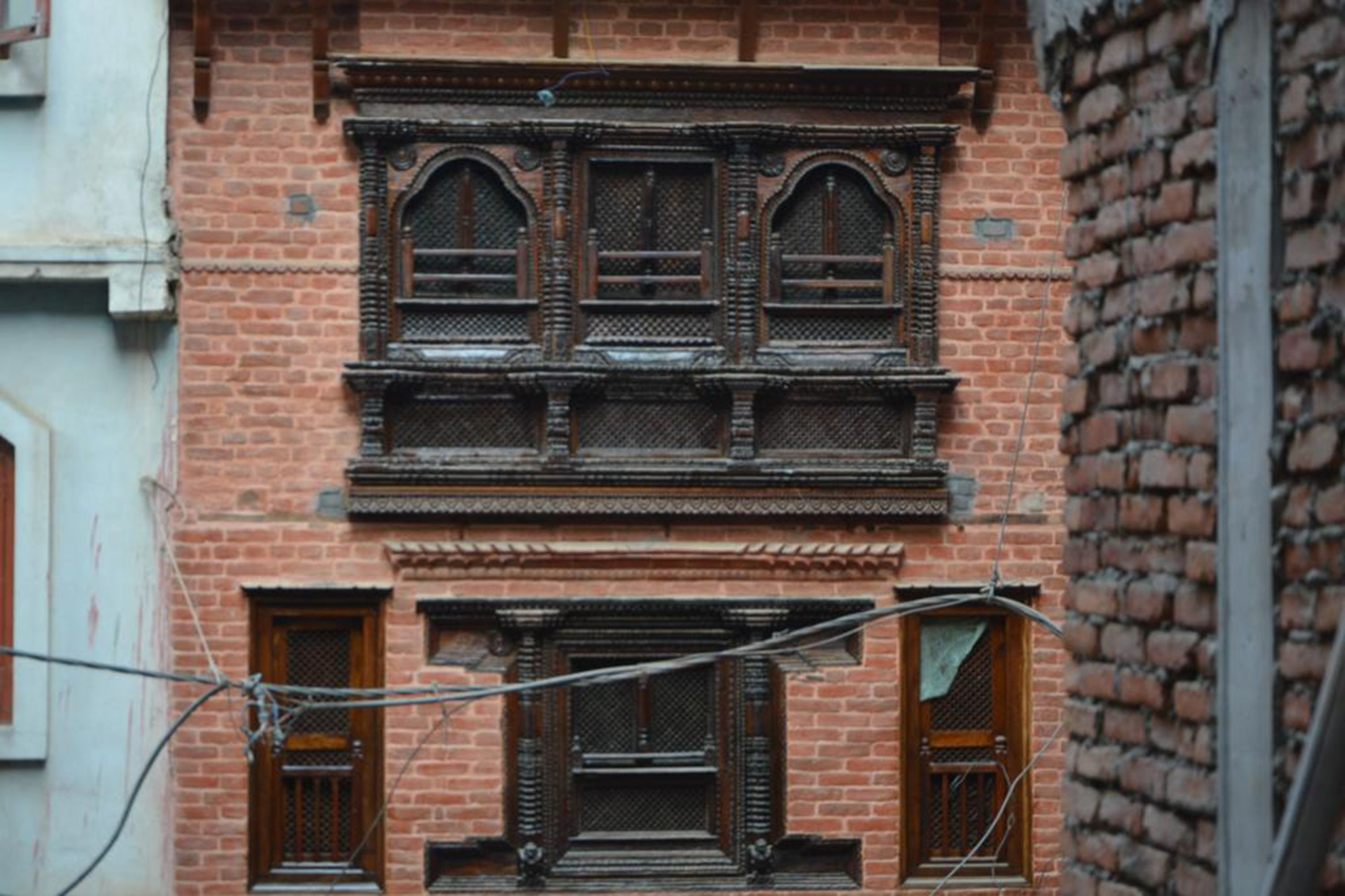 A brick building with ornate wooden window frames and a balcony.