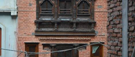 A brick building with ornate wooden window frames and a balcony.