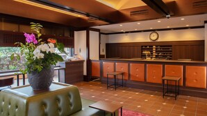 A restaurant with a green cushioned seating area, a wooden reception desk, and a clock on the wall. - Shin Iizuka Station Hotel (Iizuka)