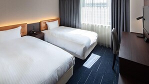 A hotel room with two beds, a desk, and a TV. - Shin Iizuka Station Hotel (Iizuka)