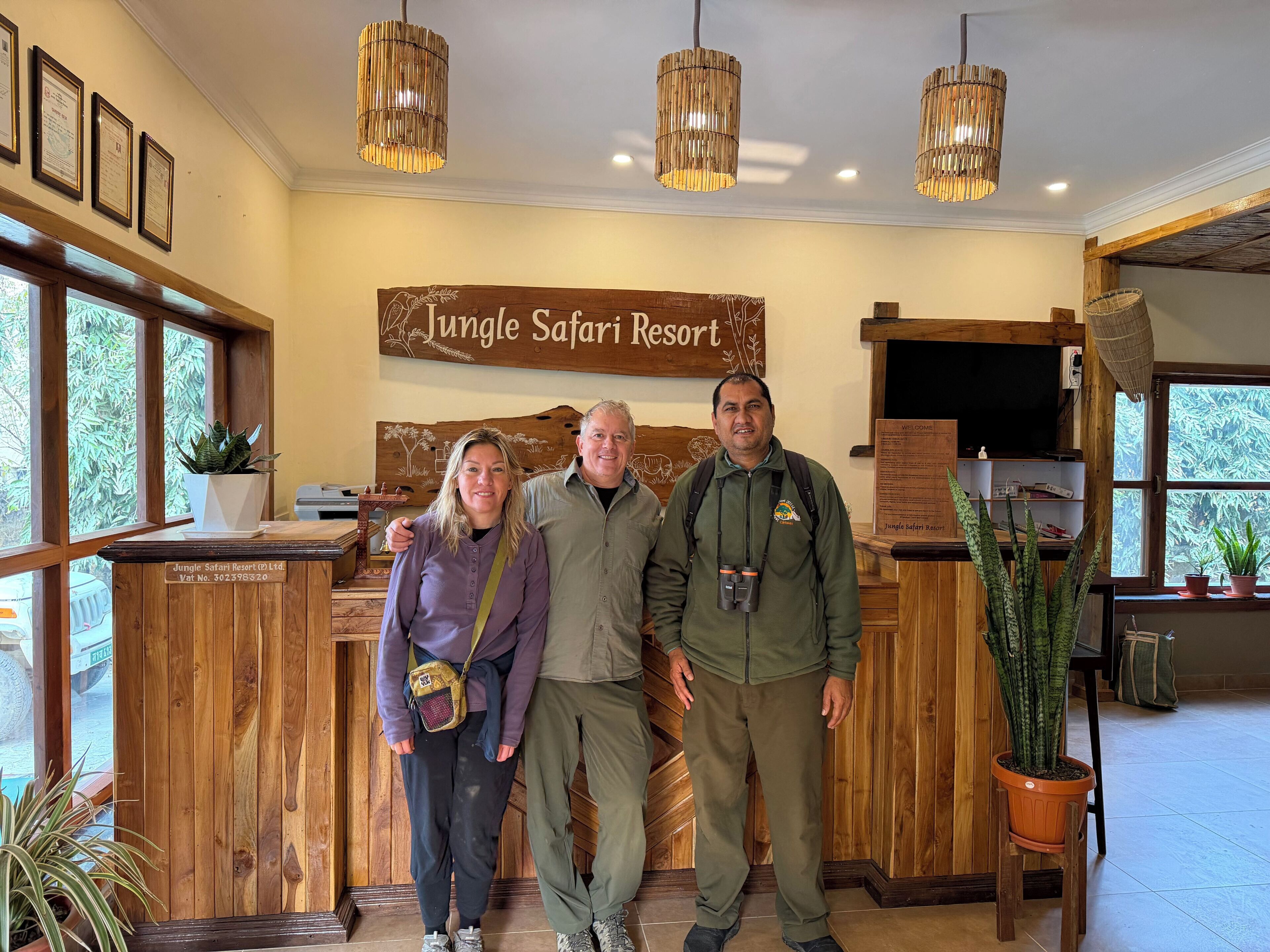 A reception desk with a wooden sign reading 'Jungle Safari Resort,' a wooden reception desk, and a welcome board.