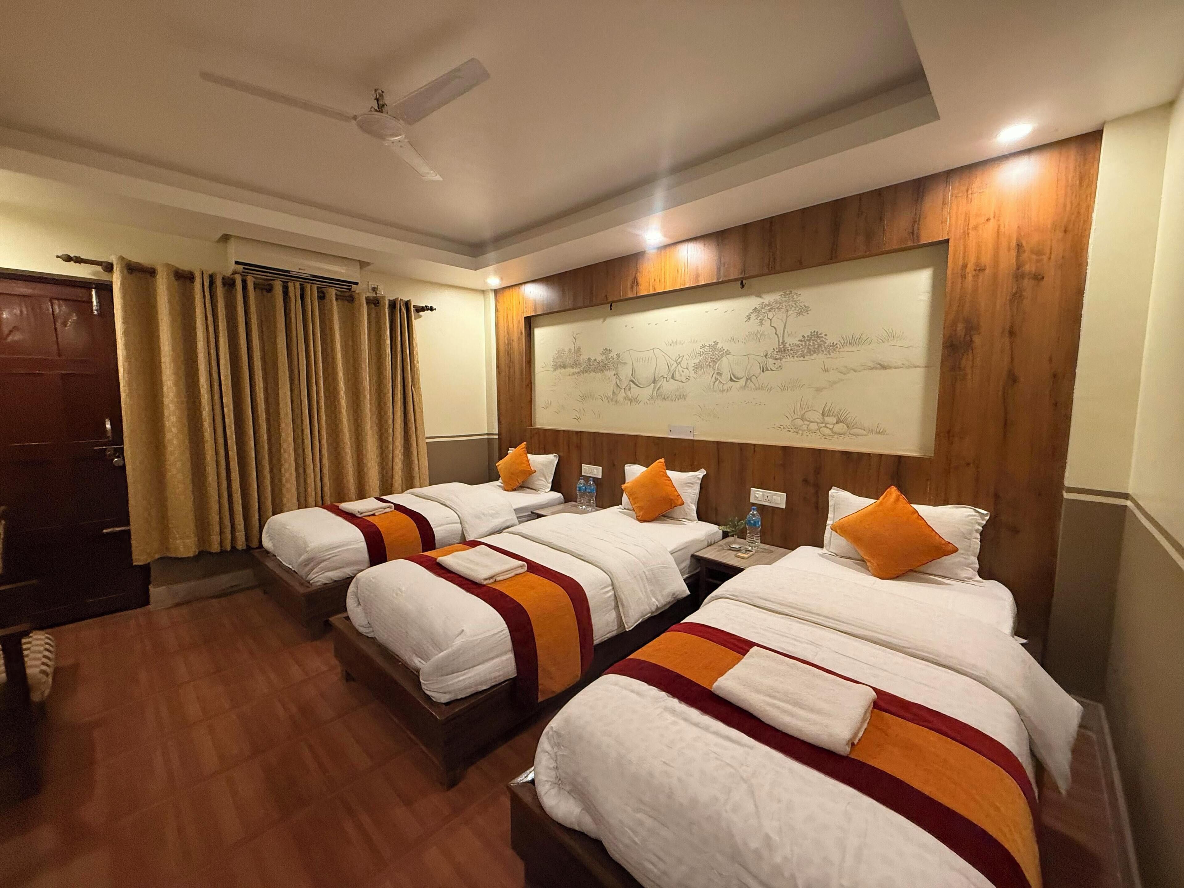 Quarto de hotel com quatro camas, ventoinha no teto, painel de parede em madeira e um grande mural.