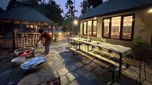 Un espace extérieur aménagé pour les repas, avec une longue table, des chaises et un barbecue.