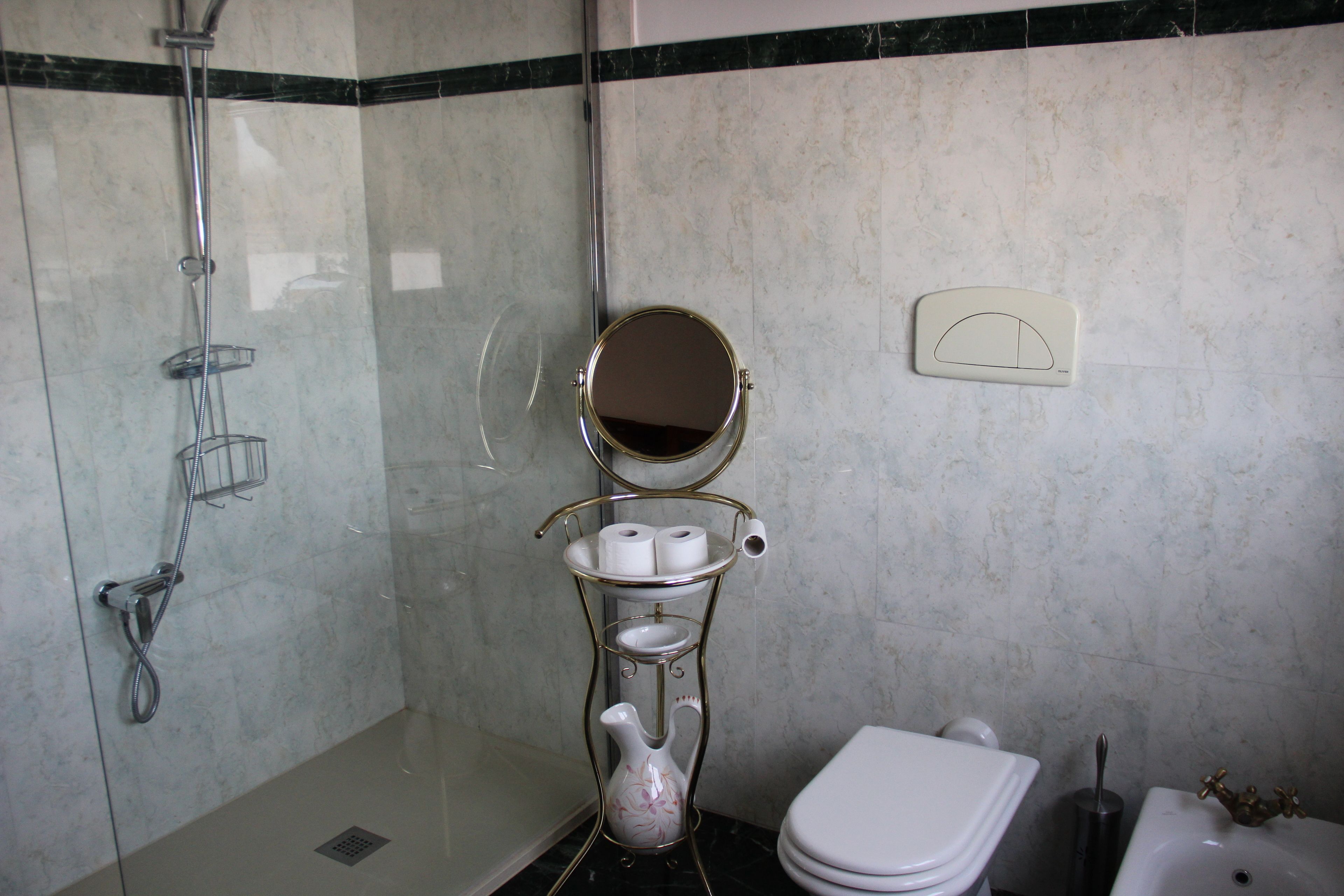 Ein Badezimmer mit Dusche, Toilette, Waschbecken und einer dekorativen Vase.