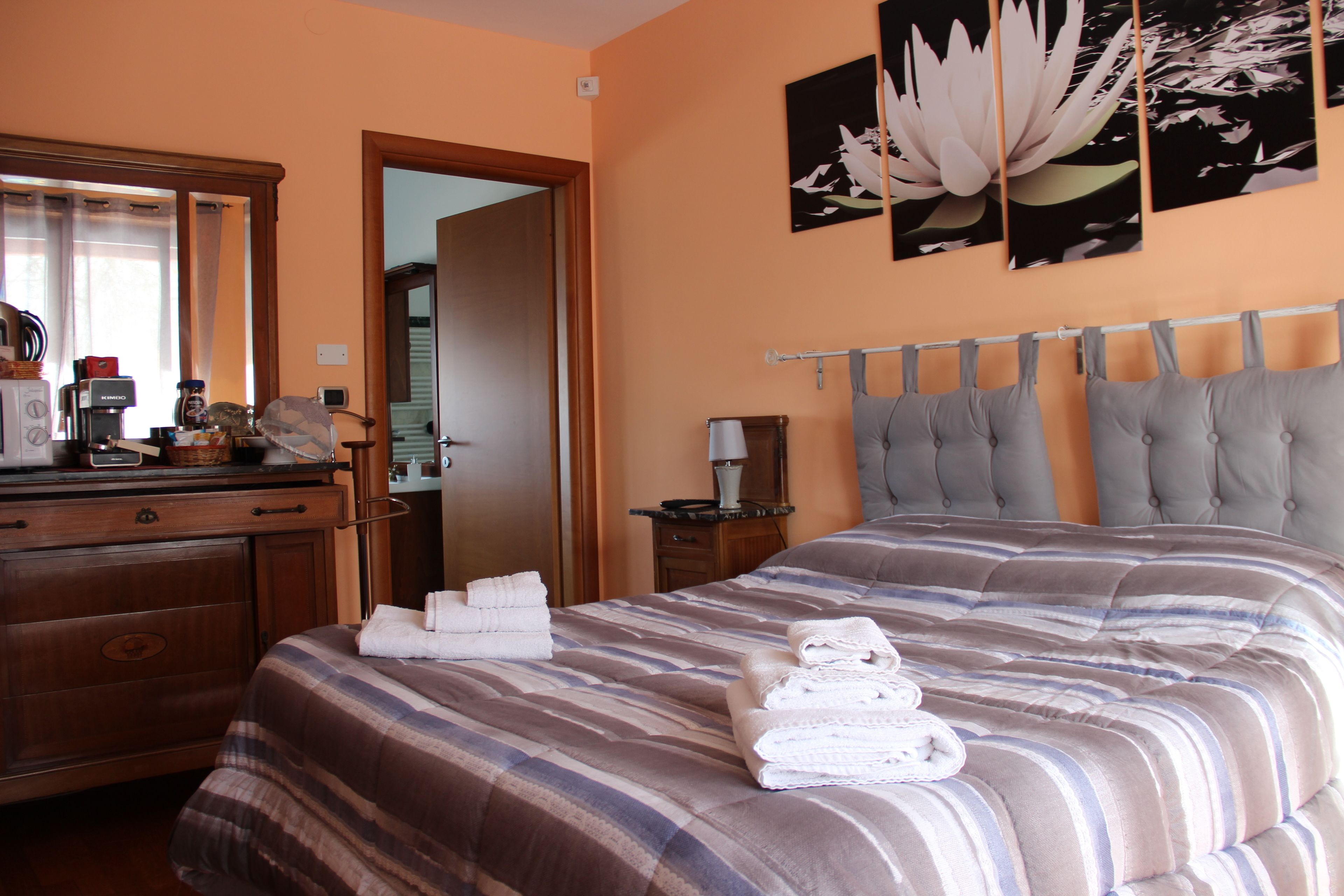 Een hotelkamer met een bed, een dressoir, een spiegel en een wand met een bloemschilderij.