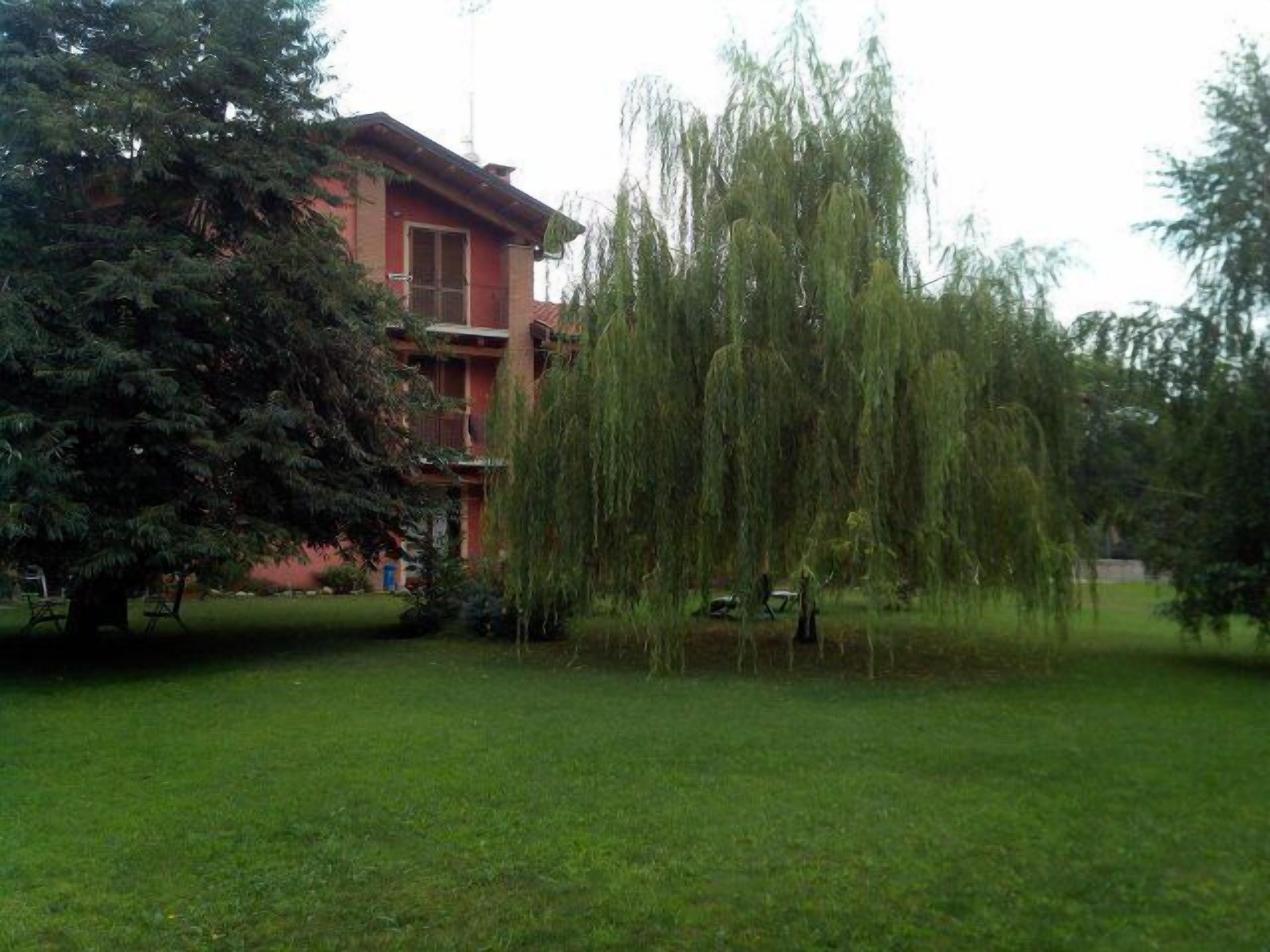 Ein Gebäude mit roter Fassade und einem großen Baum davor.