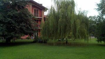 Ein Gebäude mit roter Fassade und einem großen Baum davor.