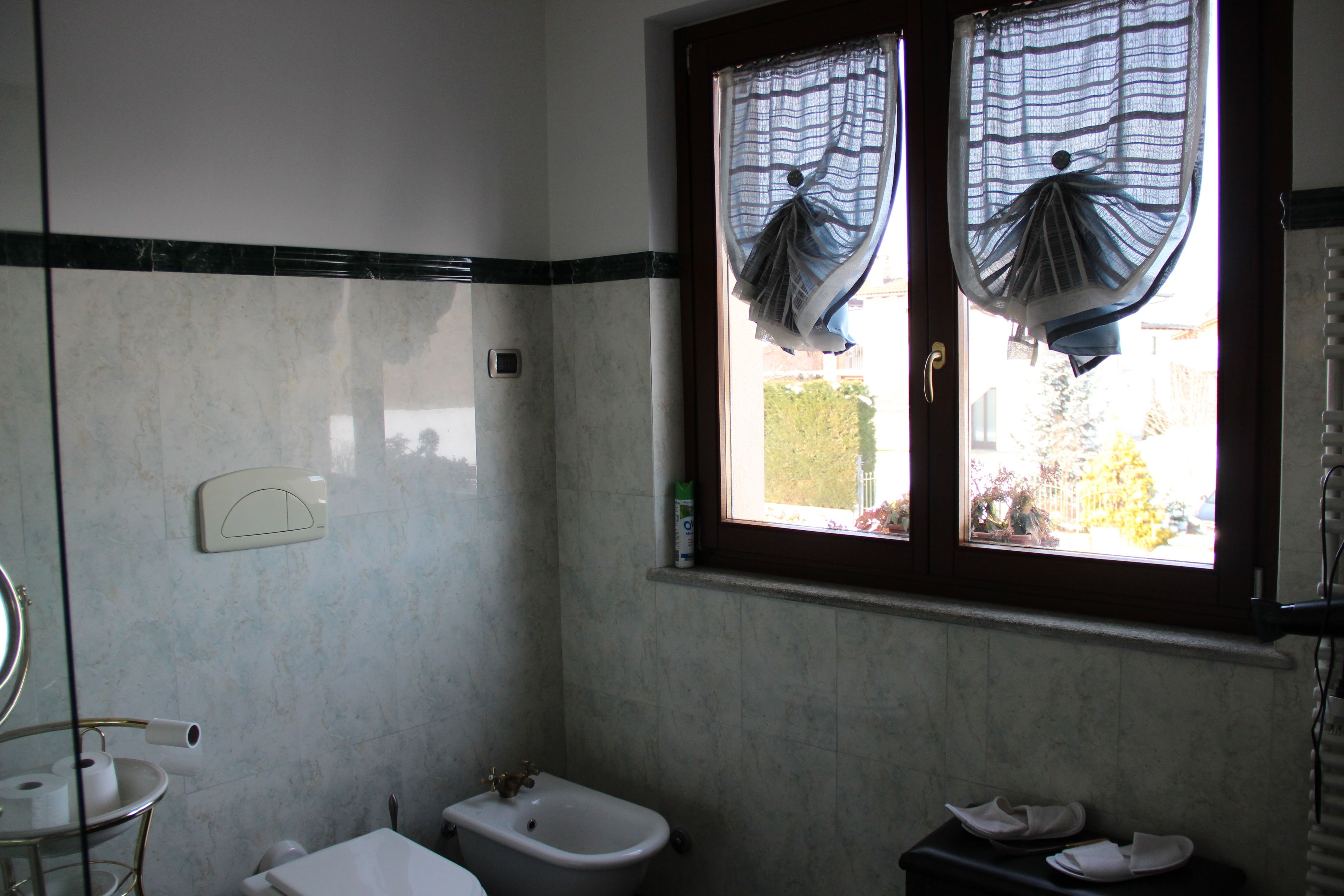 Un baño con inodoro, bidé y ventana con cortinas.