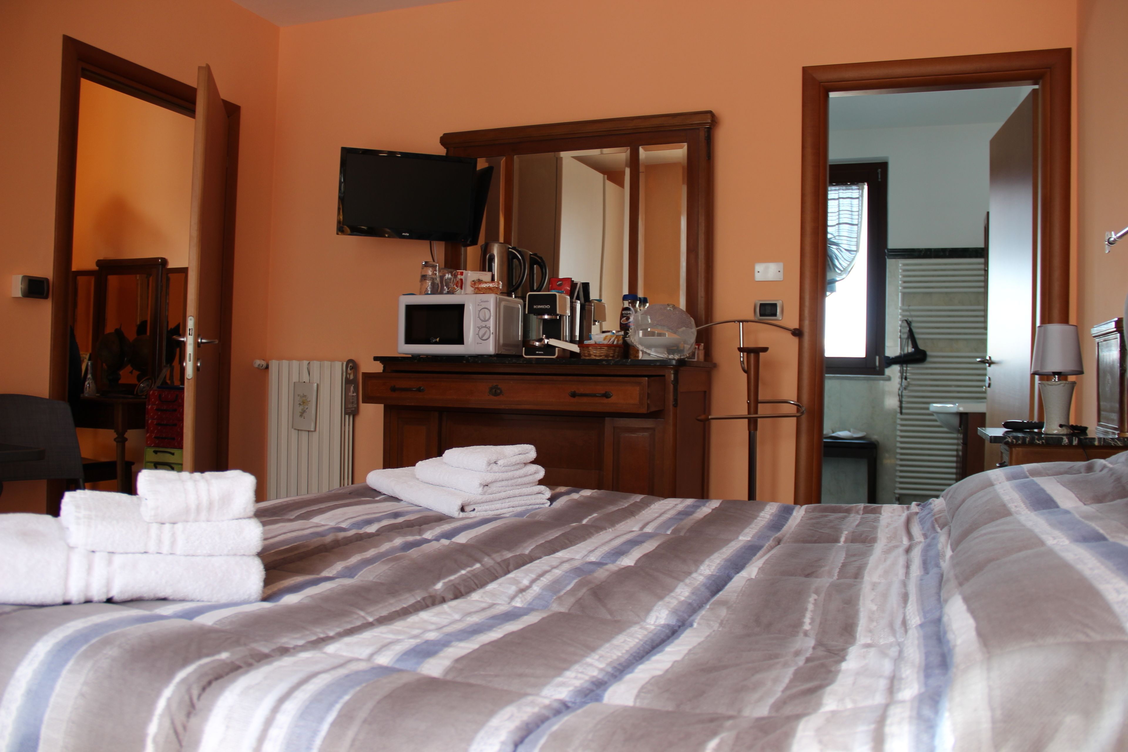 Una habitación de hotel con una cama, un tocador, un televisor y un espejo.