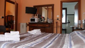 Una habitación de hotel con una cama, un tocador, un televisor y un espejo.