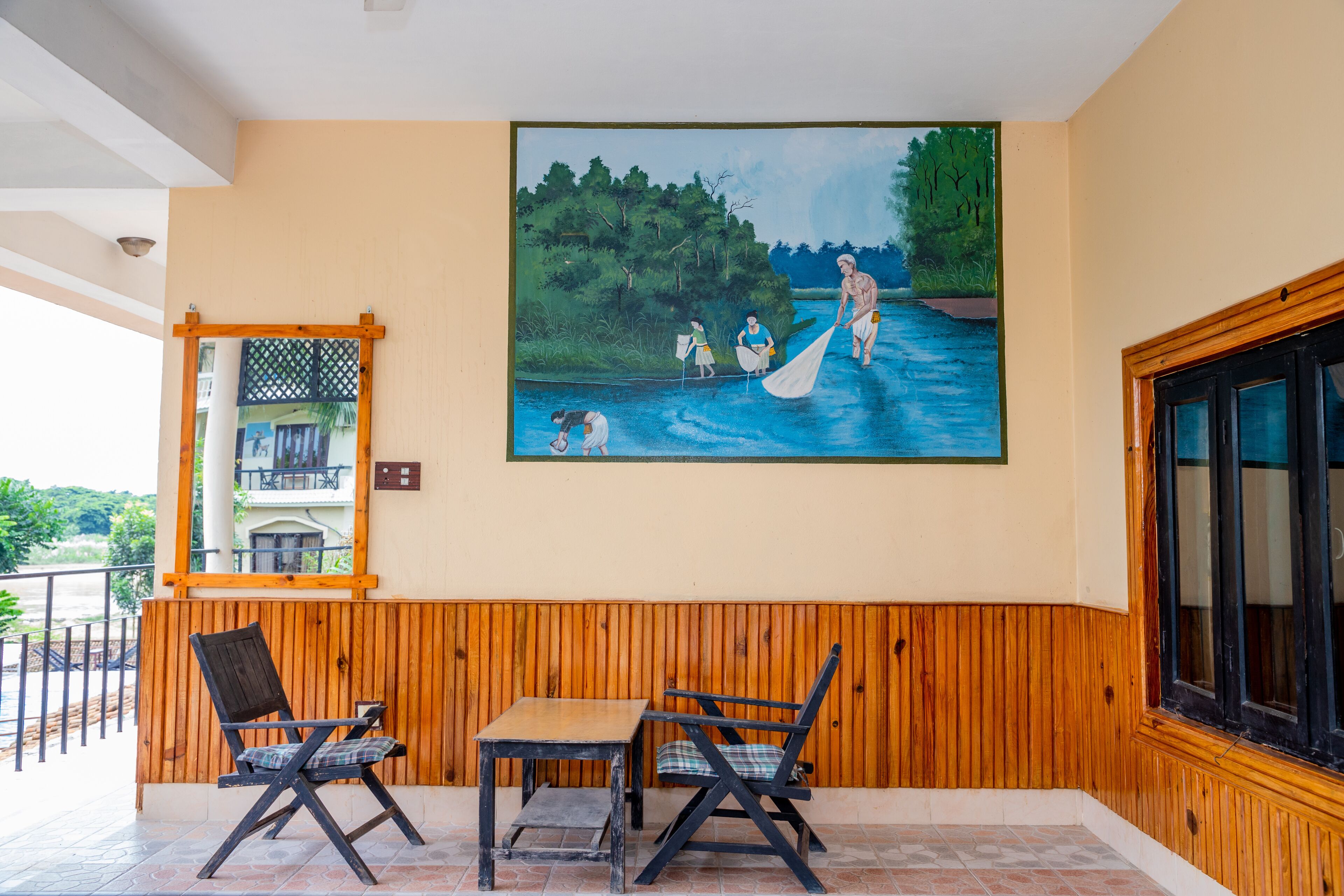 Une pièce comprenant un banc en bois, une table et un tableau représentant un paysage fluvial accroché au mur.