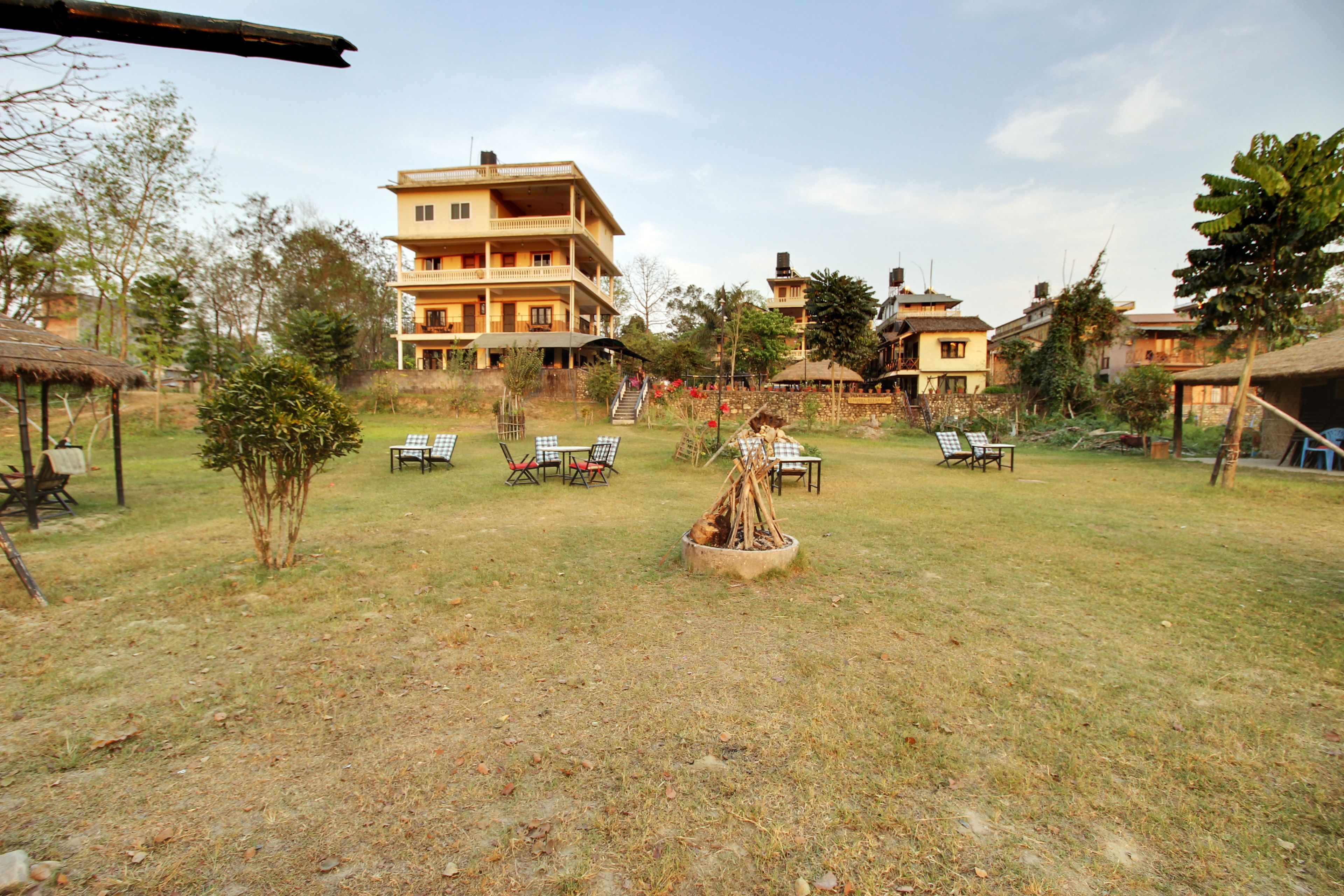 A hotel with a large building, outdoor seating area with chairs, and a fire pit.