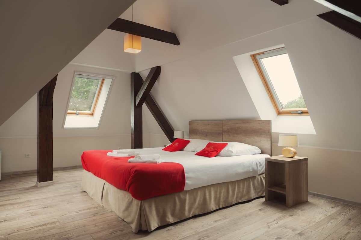 A modern bedroom with a large bed, two windows, and a wooden headboard.