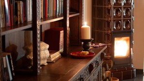 Una habitación acogedora con chimenea, estanterías y una vela sobre una mesa.