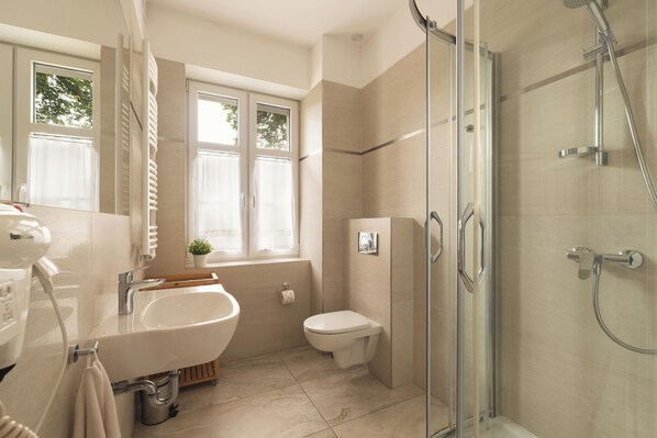 Un baño moderno con ducha de vidrio, lavamanos e inodoro.