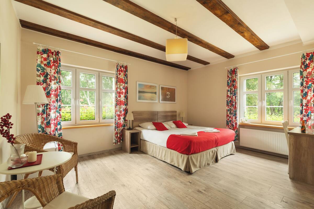 A bedroom with a bed, a chair, a table, and a window.