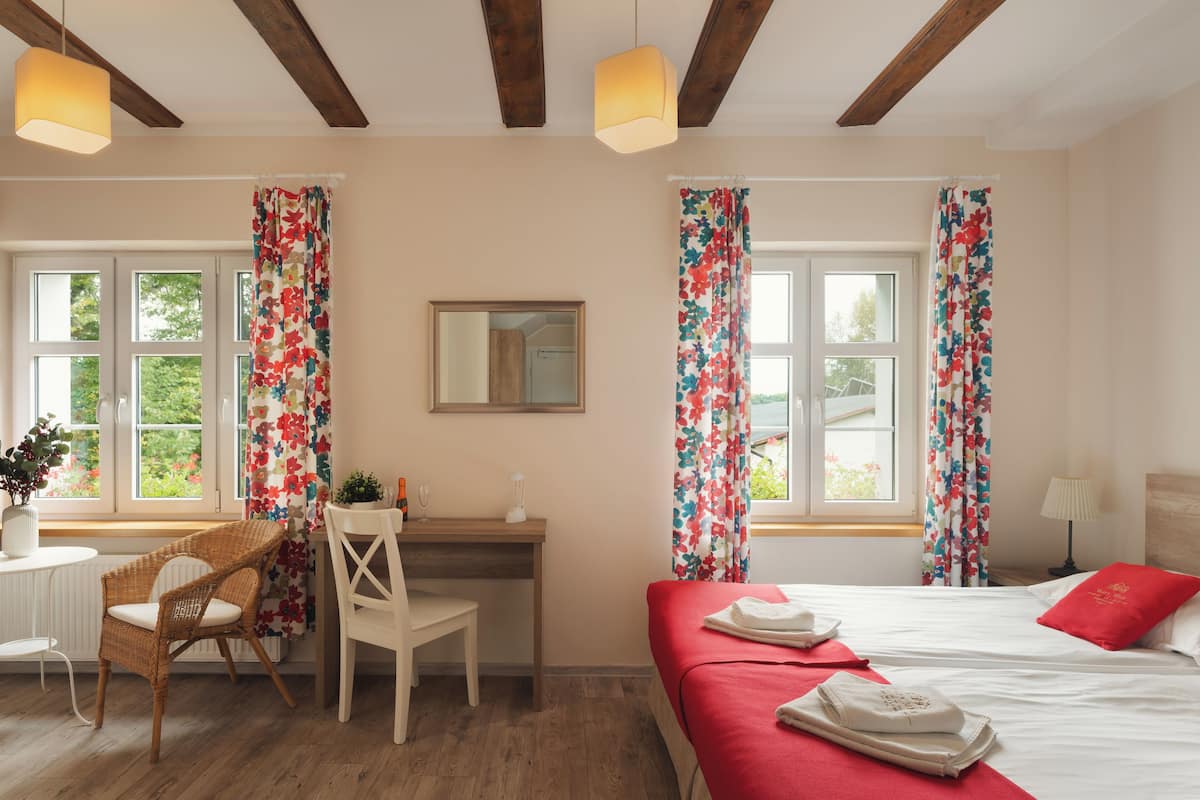 A hotel room with a bed, a desk, a chair, and a window with curtains.