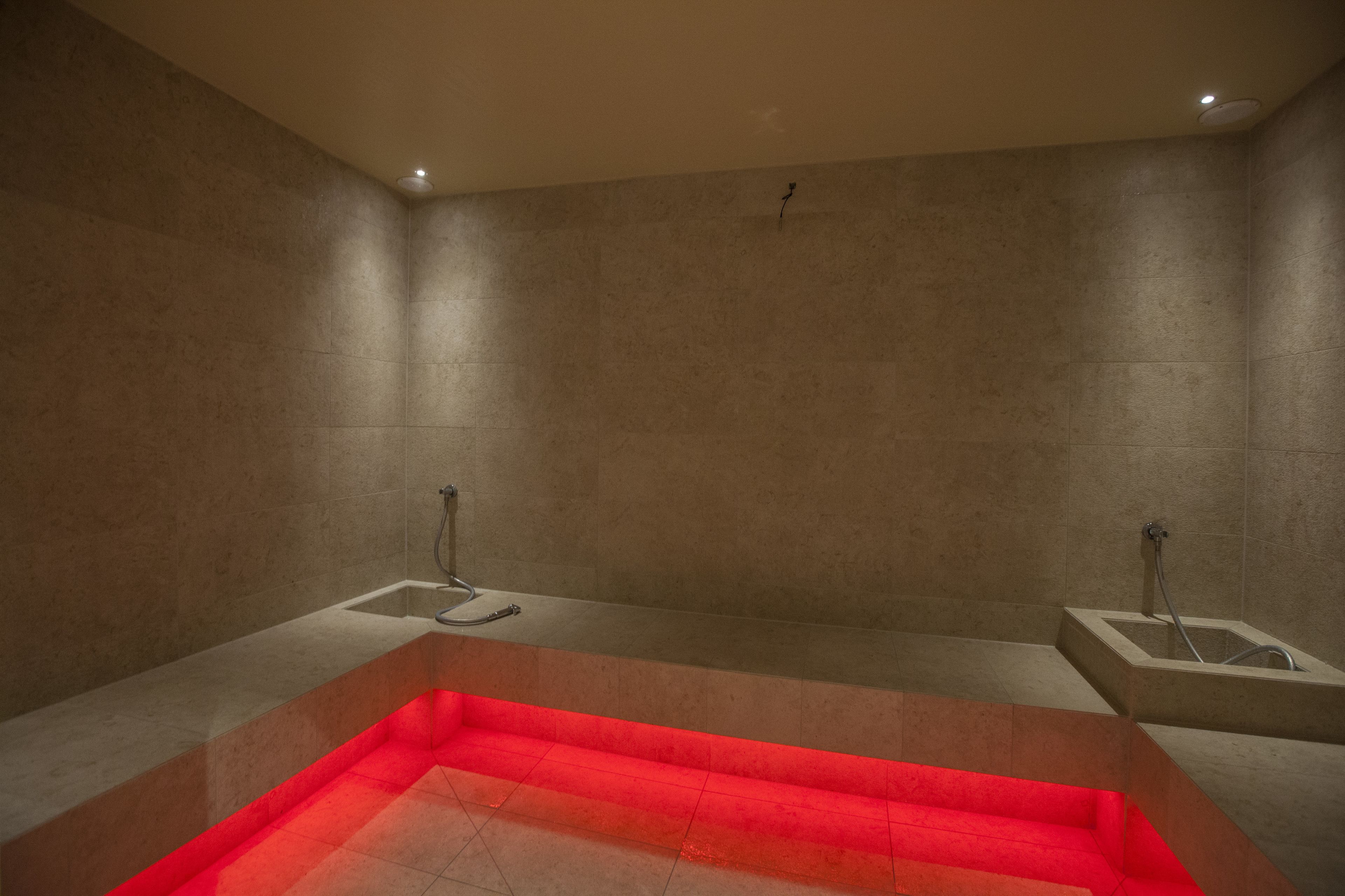 Une salle de bain moderne dotée d’un grand jacuzzi rectangulaire, de deux espaces douche séparés et d’un sol carrelé.