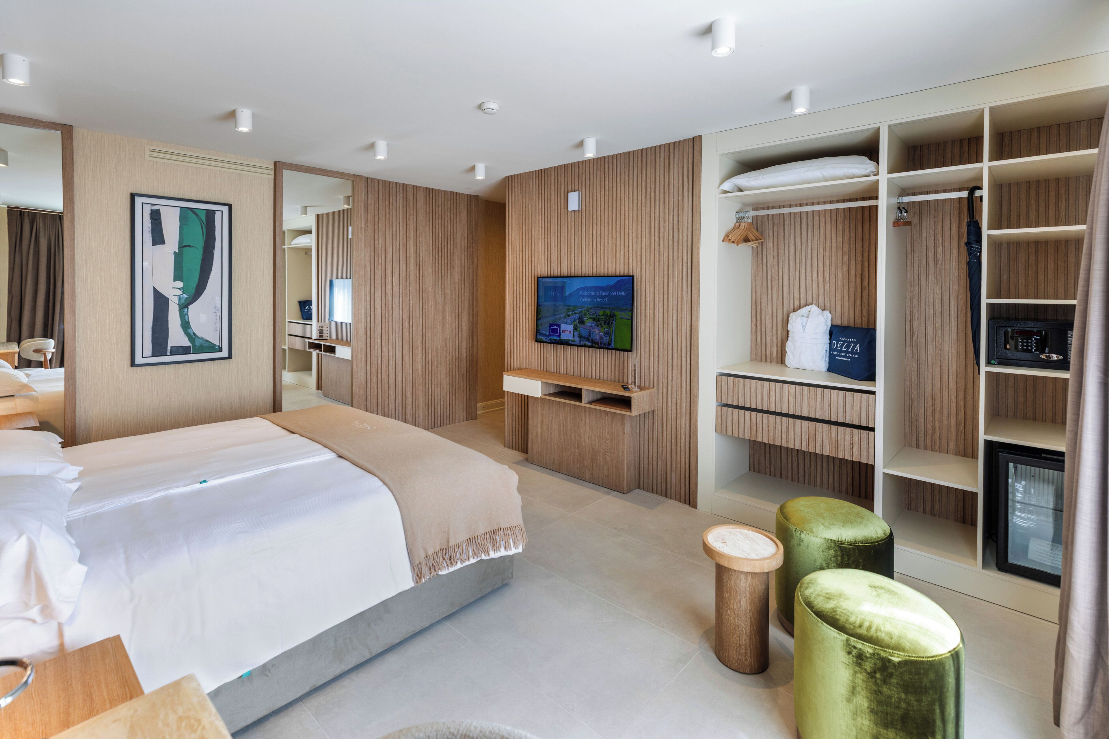 Una habitación de hotel moderna con cama, televisor, armario y escritorio.