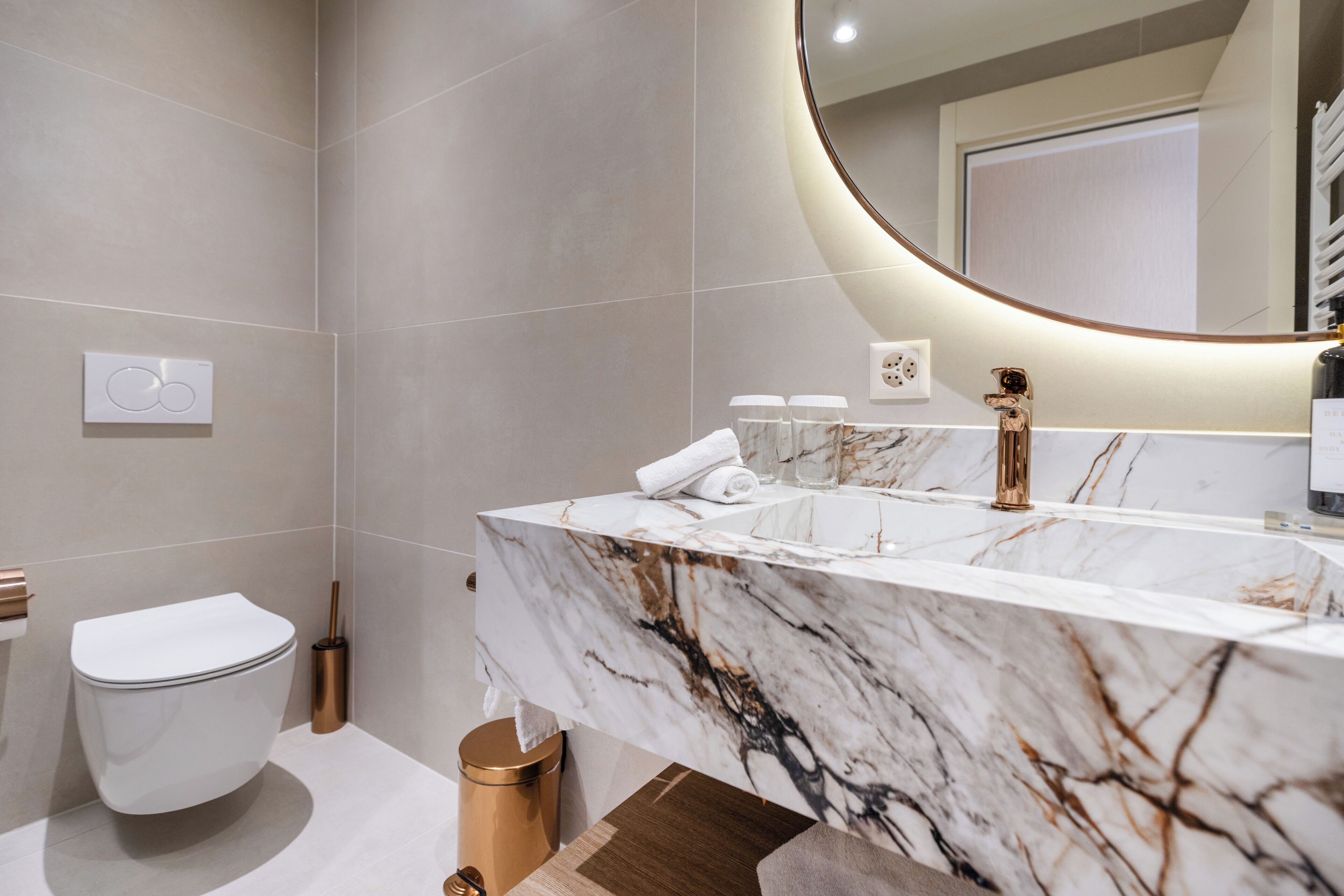 Une salle de bain moderne avec un meuble-lavabo en marbre, des toilettes et un bidet.