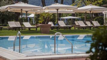 Un área de piscina con sillones de descanso y sombrillas.