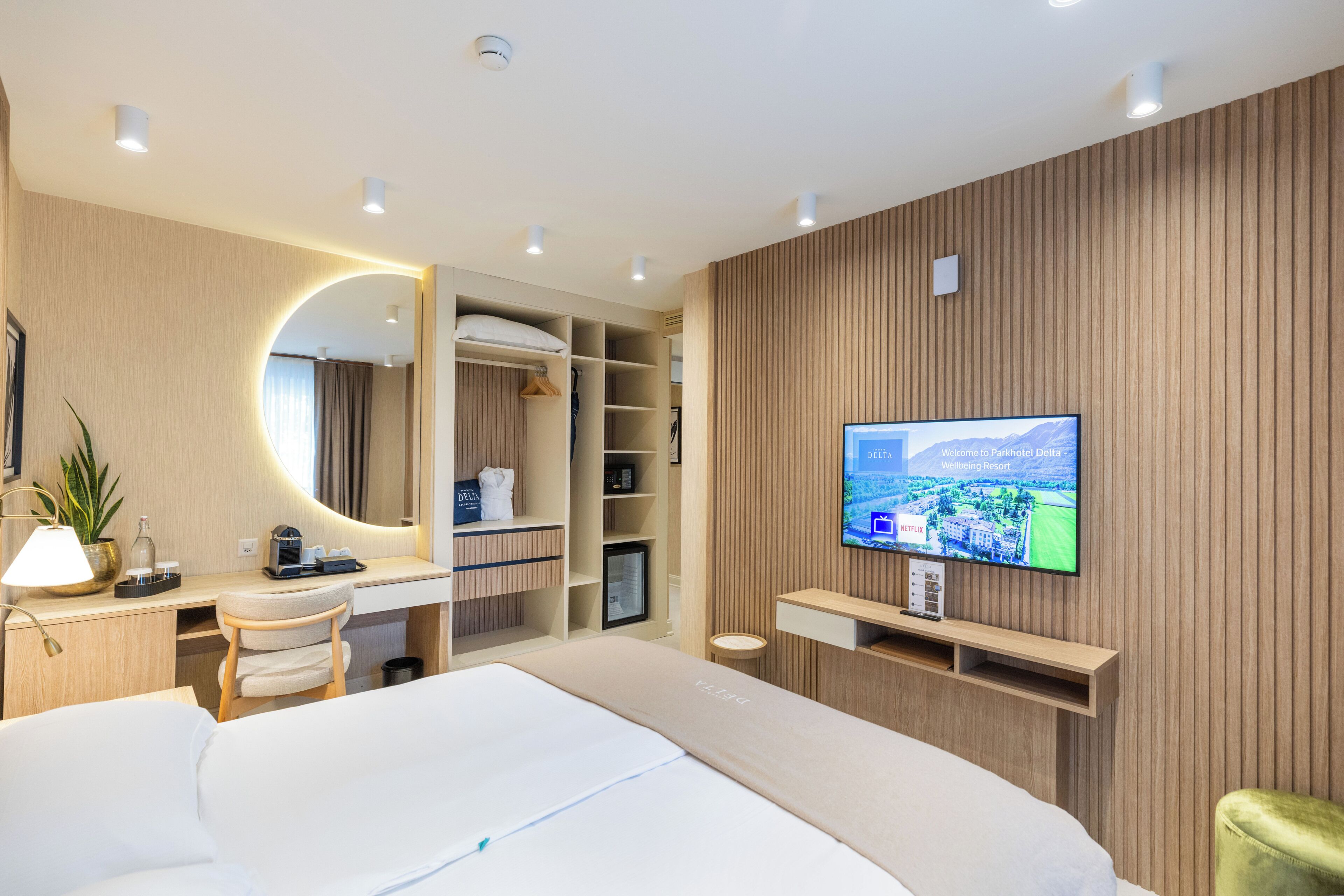 Ein modernes Hotelzimmer mit einem Bett, einem Schreibtisch, einem Fernseher und einem Kleiderschrank.
