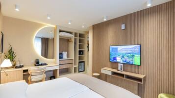 Ein modernes Hotelzimmer mit einem Bett, einem Schreibtisch, einem Fernseher und einem Kleiderschrank.