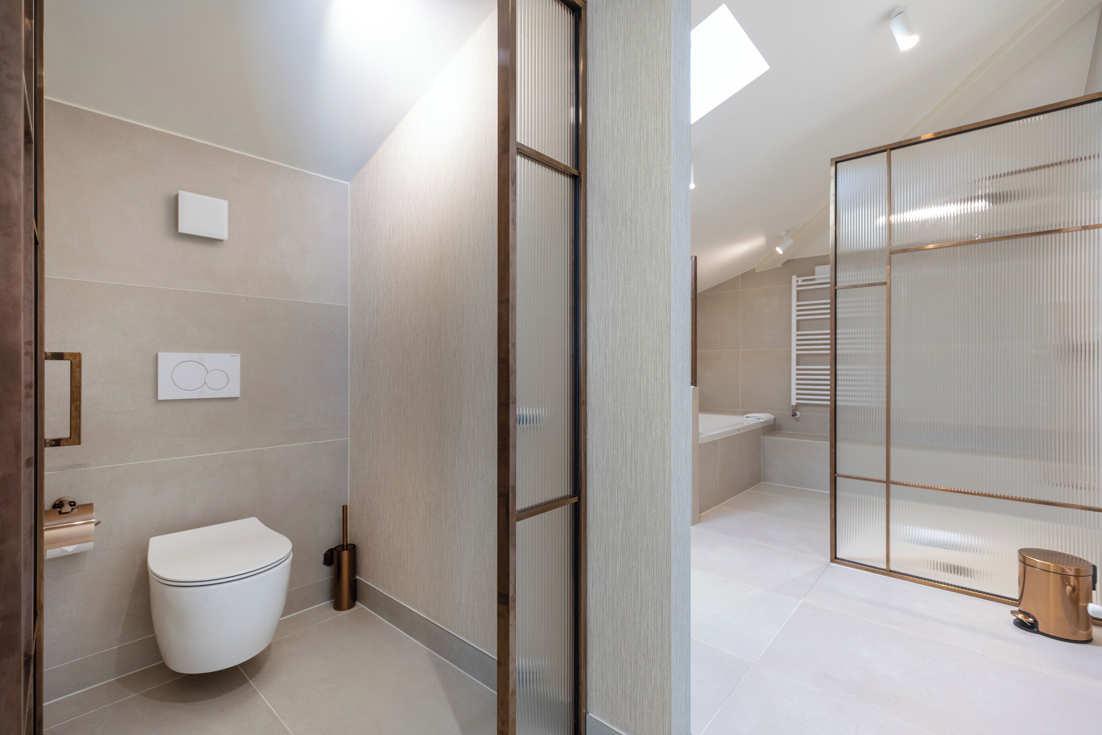 A modern bathroom with a toilet, a shower area, and a glass partition.