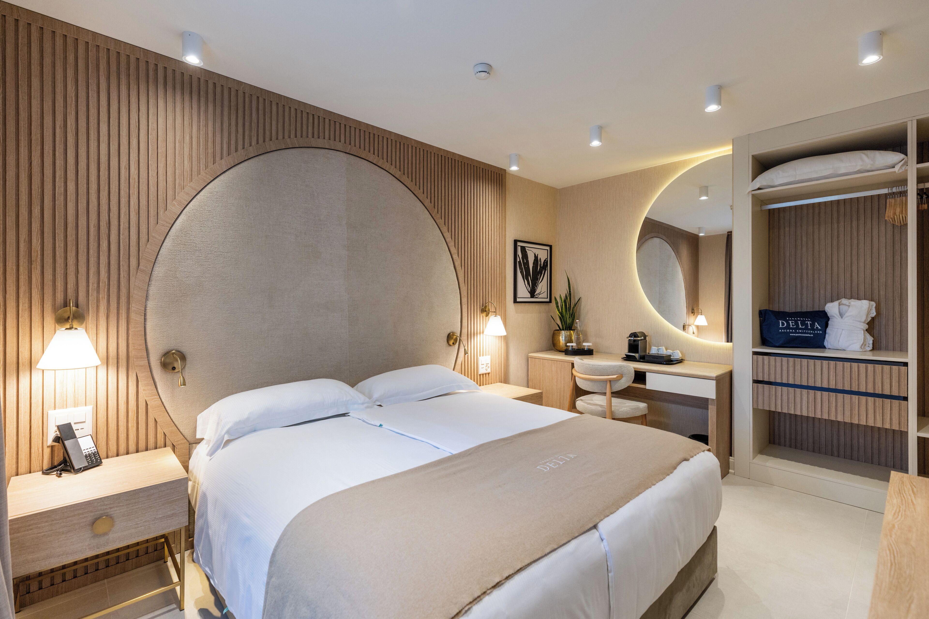 A hotel room with a large bed, bedside table, lamp, and a built-in wardrobe.