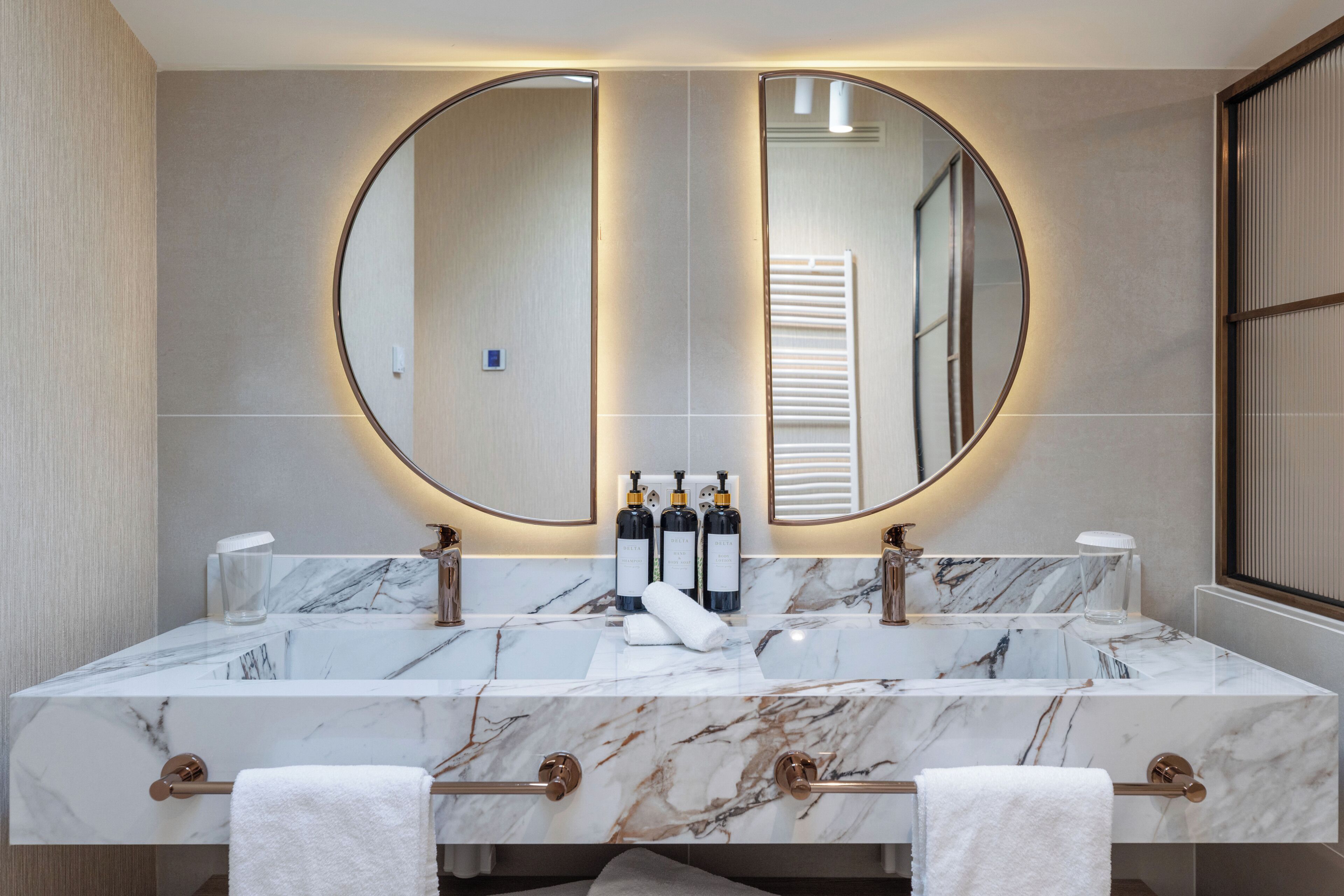 A bathroom with a large mirror, two sinks, and toiletries.