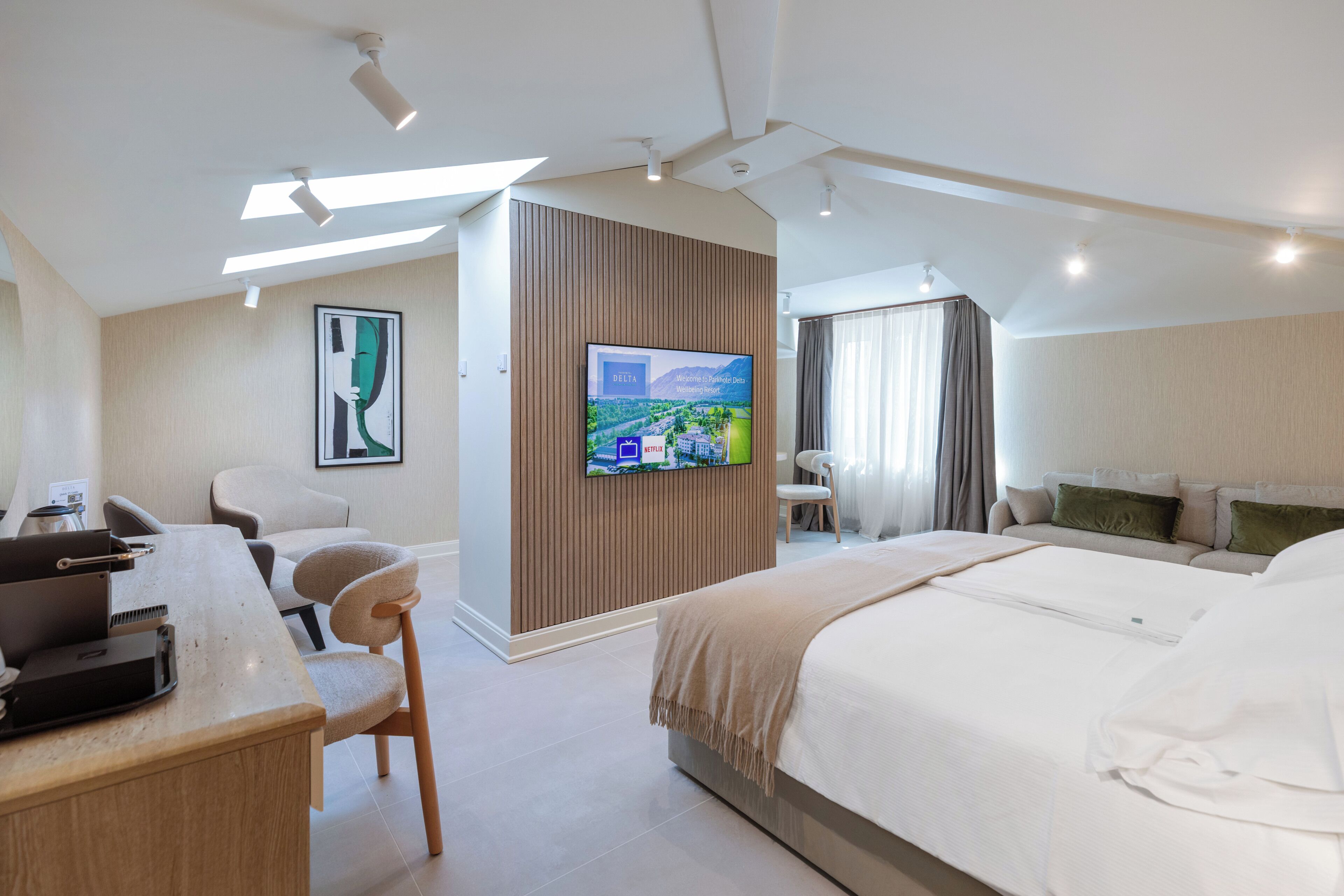 Une chambre d’hôtel moderne équipée d’un lit, d’un bureau, d’une chaise, d’une télévision et offrant une vue sur l’extérieur.