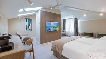 Une chambre d’hôtel moderne équipée d’un lit, d’un bureau, d’une chaise, d’une télévision et offrant une vue sur l’extérieur.
